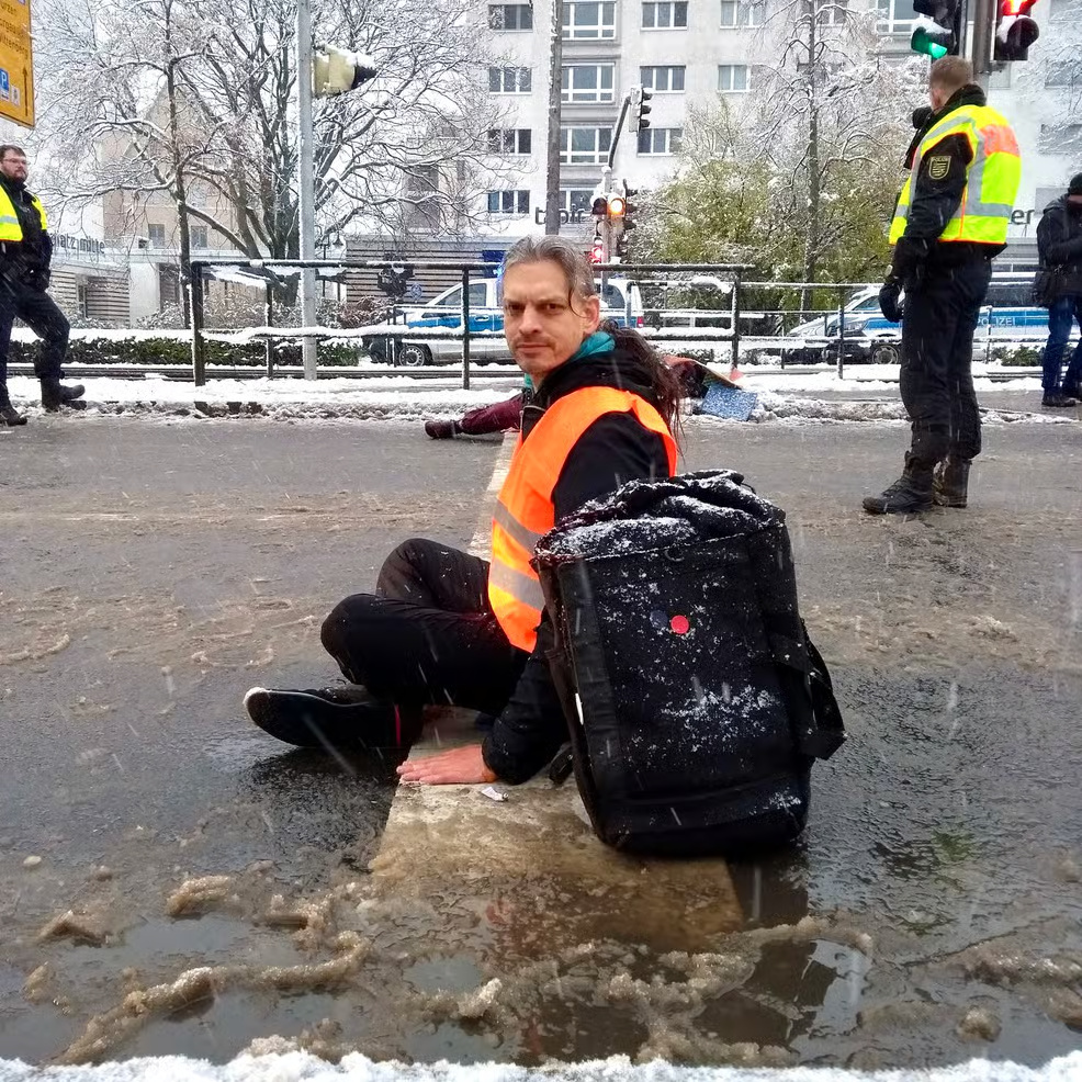 Christian Bläul sitzt bei einem Klimaprotest in Leipzig im Schneematsch