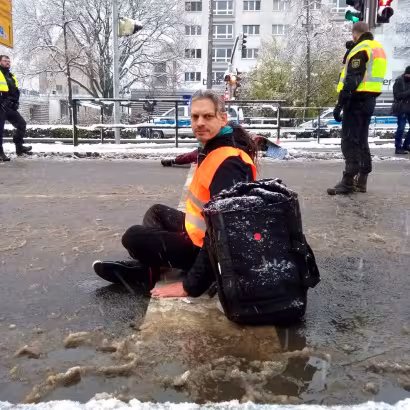 Christian Bläul sitzt bei einem Klimaprotest in Leipzig im Schneematsch